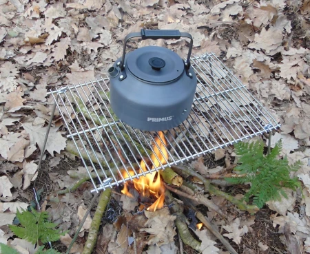 Składany ruszt na ognisko (grill turystyczny) Fox Outdoor stalowy 38x25 cm - złożony, zaprezentowany z czajnikiem w lesie